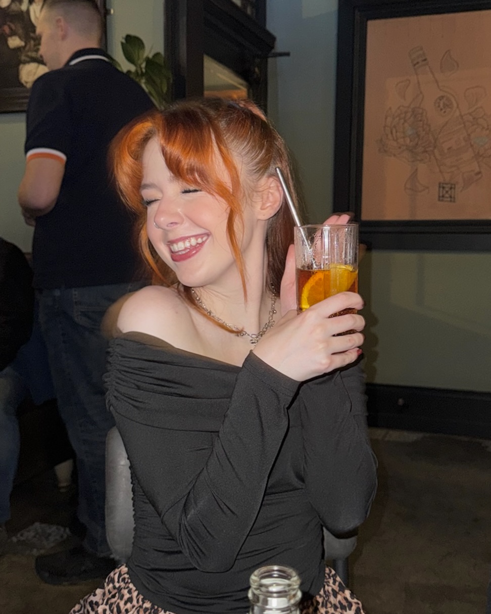 Bethan smiling with a drink at a bar